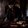 Occult practitioner at ritual altar organizing grimoires