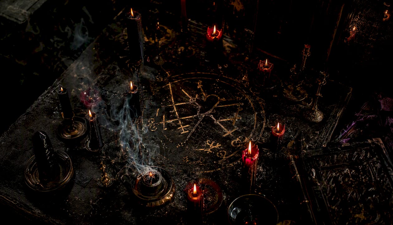 Hands arranging candles and sigil on altar