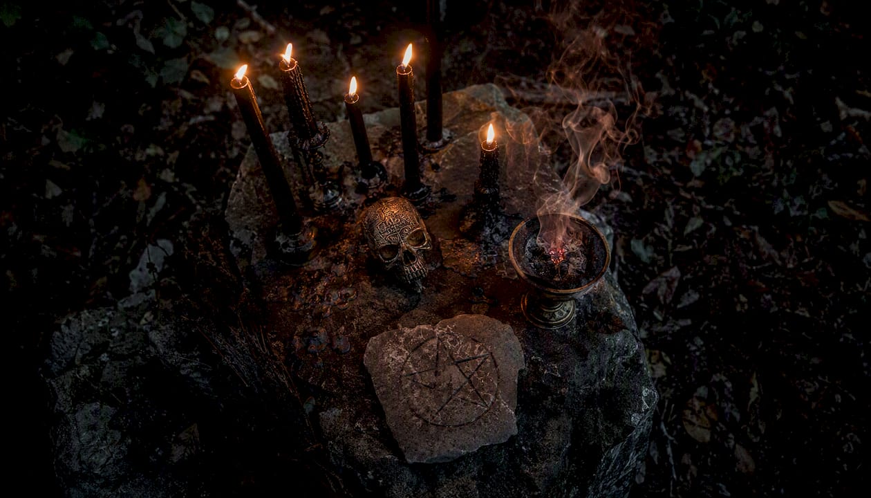Black candles and ritual symbols on stone altar