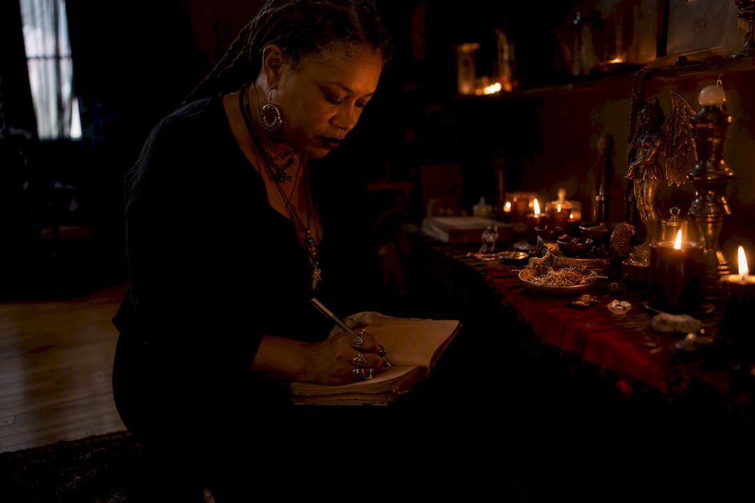 Practitioner journaling by candlelight near altar