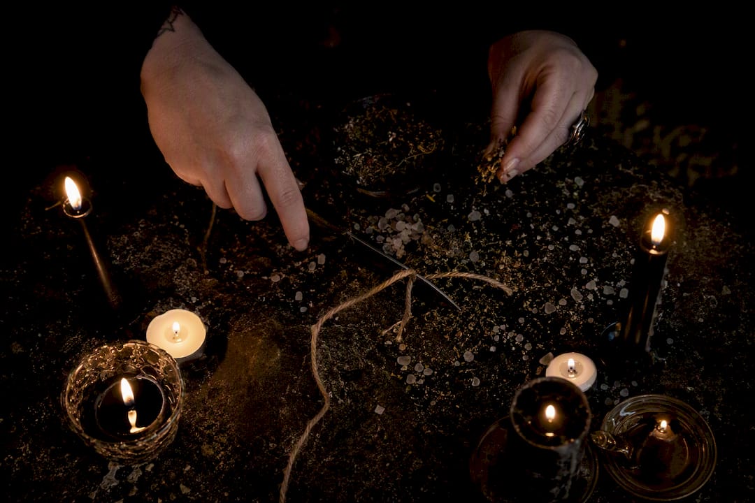 Hands performing cord cutting ritual with candles